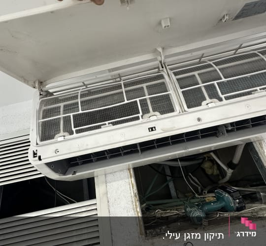 מזגן פתוח עם מסננים, יד מחזיקה את המכסה